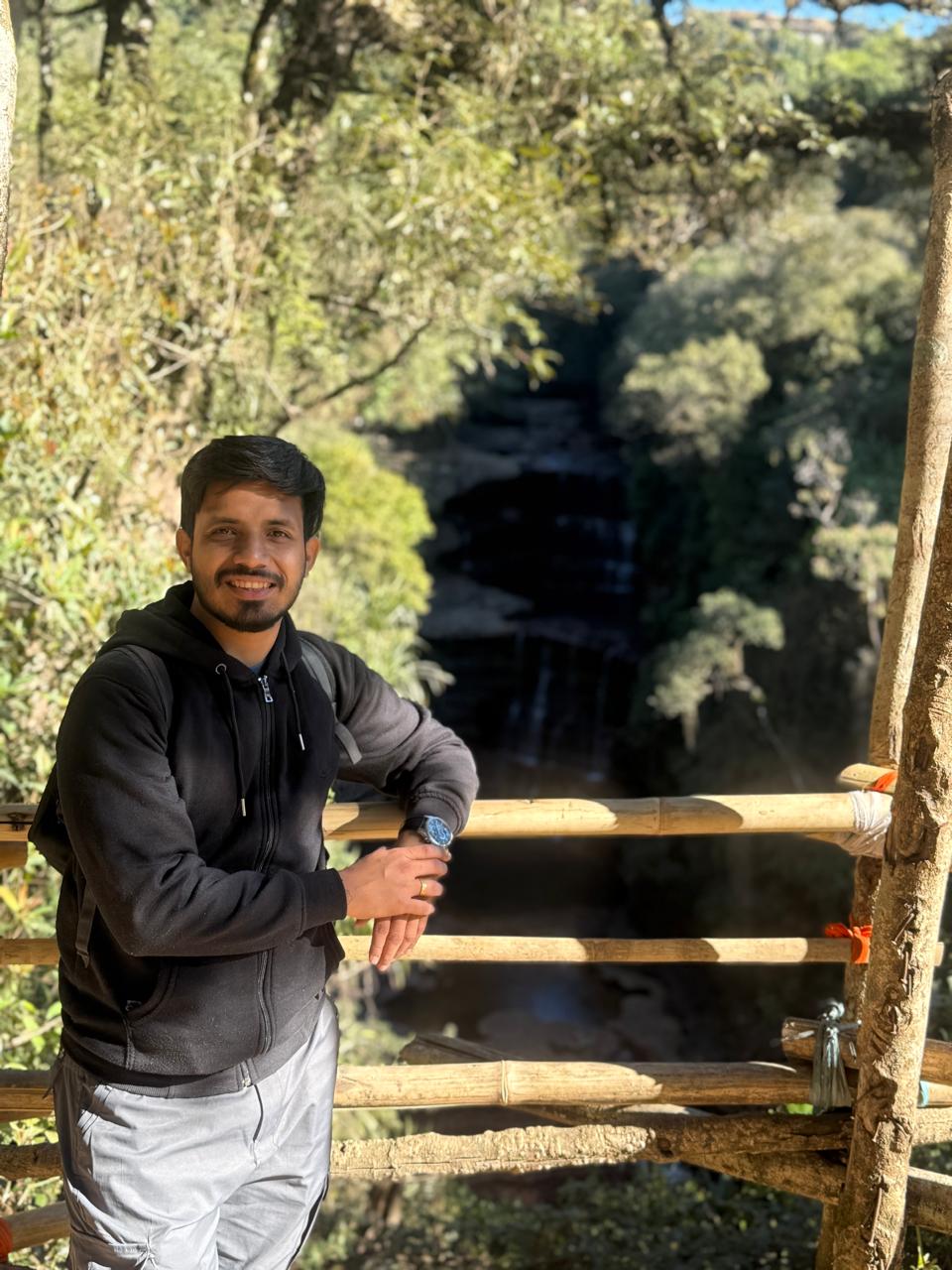 Founder of Paranjape Tours standing outdoors near a waterfall viewpoint